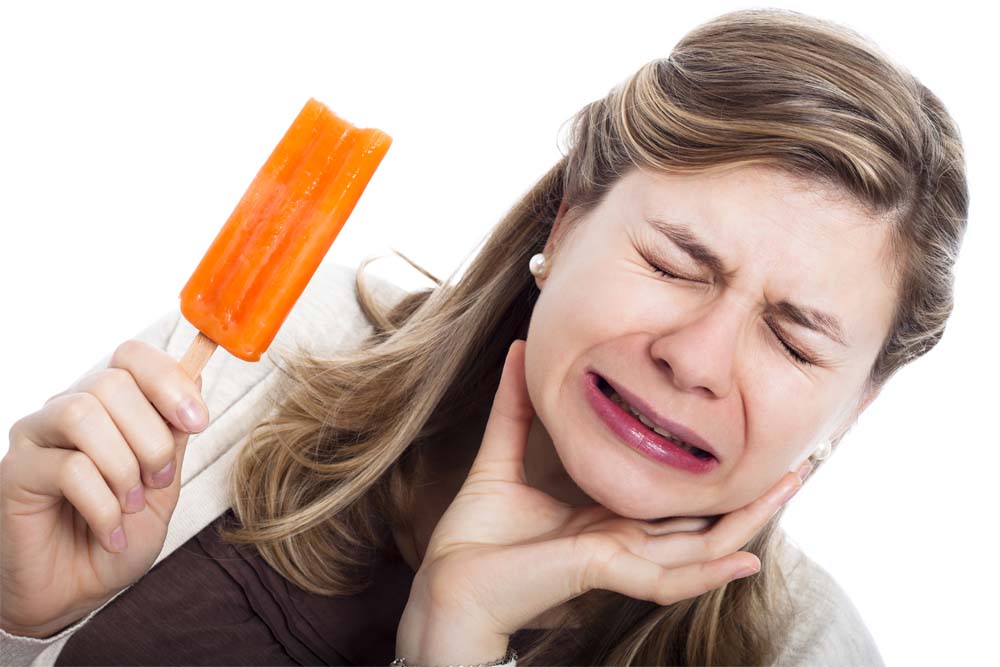 Young woman with sensitive teeth eating popsicle